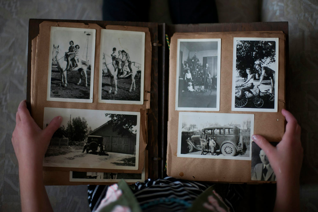 A person opening a photo album of black and white photographs